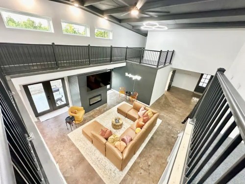 Spacious modern living room with a large sectional sofa, coffee table, and a view of a balcony above.