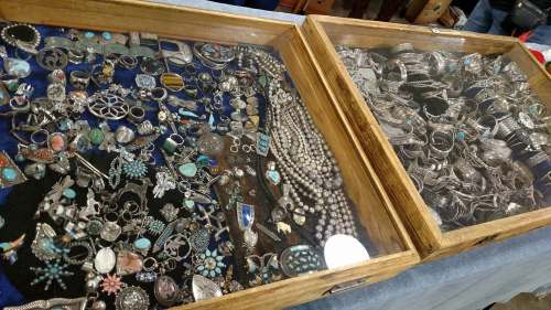 Two wooden display cases filled with various silver jewelry pieces, including necklaces, bracelets, and rings.