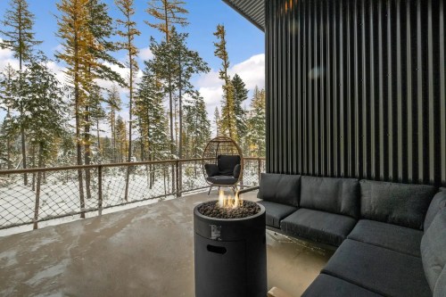 Cozy outdoor seating area with a fire pit, surrounded by snowy trees and a clear blue sky.