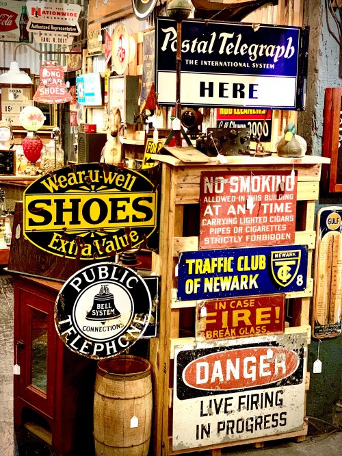 A collection of vintage signs, including "Wear-u-well Shoes," "Public Telephone," and "Danger: Live Firing in Progress."