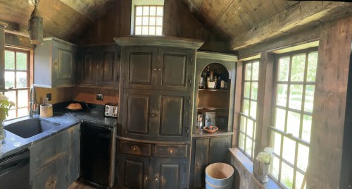 Cozy kitchen with wooden cabinets, a black sink, and large windows letting in natural light.