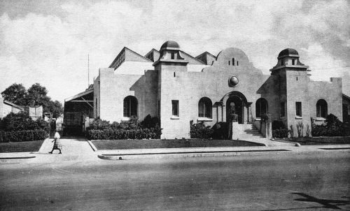 Historic building with a distinctive architectural style, featuring domed towers and a landscaped entrance.