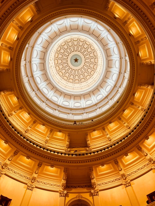 A view of a grand dome ceiling with intricate designs and warm lighting, showcasing architectural elegance.