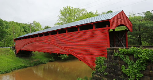 a bright red bridge spans across a river in west virginia
