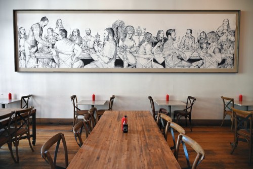 Restaurant with mural of people at full tables enjoying a meal