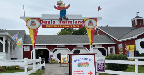 Entrance to Davis Farmland, featuring colorful signage and a red barn, welcoming visitors to the children's discovery farm.