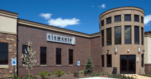 Modern building exterior with a round tower, large windows, and a sign reading "element." Clear blue sky above.