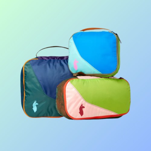 Three colorful packing cubes in blue, green, and pink, arranged on a gradient background.