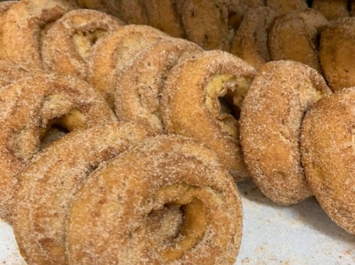 A close-up of freshly baked, cinnamon-sugar coated donuts arranged in a row.