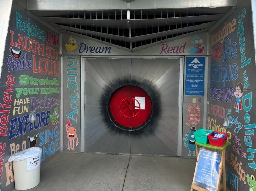 Colorful entrance to a building with playful text and a large red circular door, inviting creativity and imagination.
