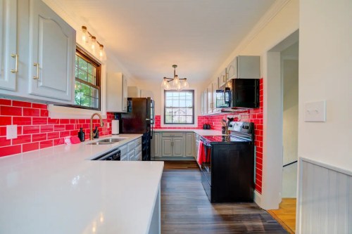 Modern kitchen featuring red tile backsplash, gray cabinets, and stainless steel appliances. Bright and inviting space.