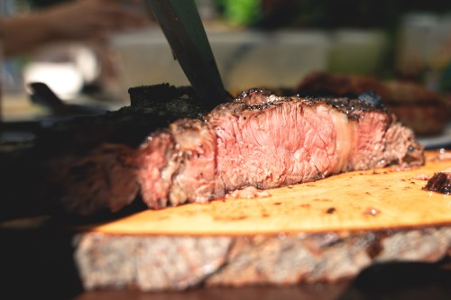 A close-up of a perfectly cooked steak, sliced on a wooden cutting board, showcasing its juicy, pink interior.
