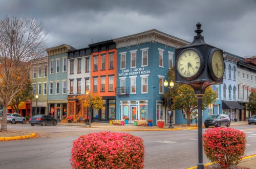 Town clock at a busy intersection in downtown Portsmouth Ohio, flanked on two sides by beautiful red bushes. Multicolored facades on the street of early 20 century architecture gives this scene a small town persona. 2nd Street Portsmouth, Ohio Ohio River Scenic Byway Photo taken on October 28, 2023