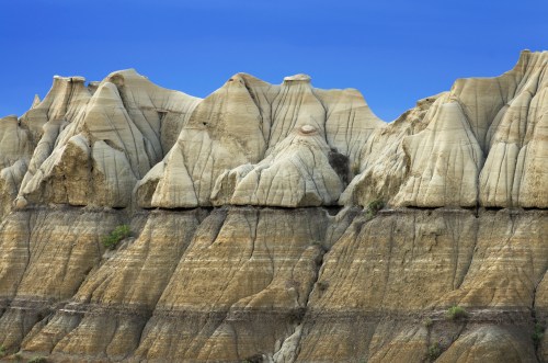 Layered rock formations with distinct ridges and a clear blue sky above.
