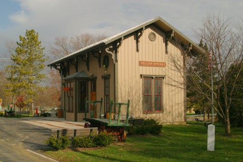 A beige historic railroad station in Yellow Springs, Ohio against a gray overcast sky.