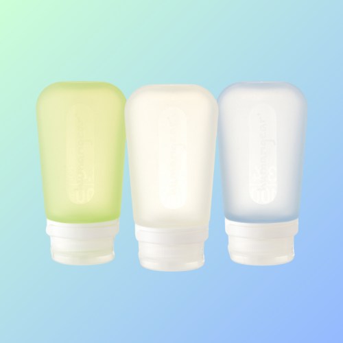 Three travel-sized squeeze bottles in green, white, and blue against a gradient background.