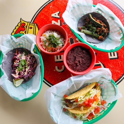 A colorful spread of tacos, beans, and toppings on a vibrant table, featuring blue corn tortillas and fresh ingredients.