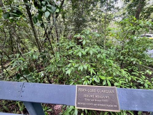 A plaque titled "Fern Lore Guardian" is surrounded by lush greenery in a forested area.