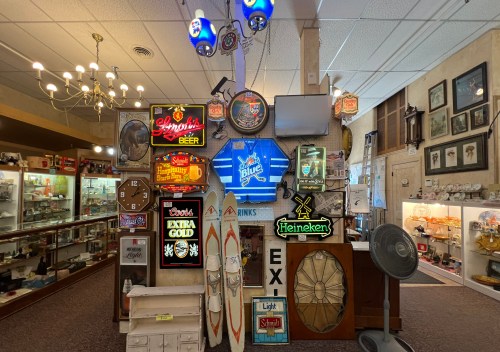 A collection of vintage signs and memorabilia displayed in a shop, featuring beer brands and decorative items.