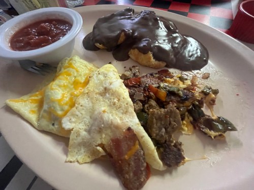 A plate with an omelet, a biscuit topped with chocolate, and a side of salsa.