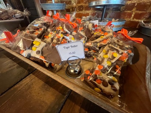 A wooden tray filled with packaged Tiger Butter treats, topped with colorful candy, priced at $5.50.