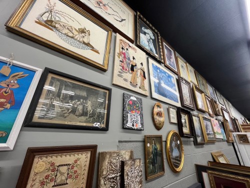 A wall filled with various framed artworks and photographs, showcasing diverse styles and subjects.