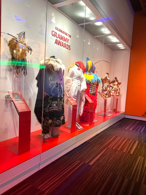 Display of colorful Grammy Awards costumes in a glass case, celebrating the artistry of music's biggest night.