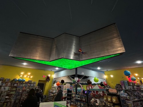 A colorful game store interior featuring a unique green-lit ceiling design and various decorations.