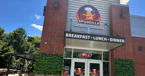 Exterior of Spudzilla restaurant featuring a sign with a cartoon potato chef, open for breakfast, lunch, and dinner.