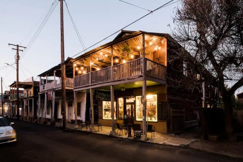 A charming street view of a wooden building with string lights, showcasing a cozy atmosphere at dusk.