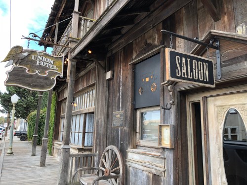 Exterior of a rustic wooden building featuring signs for "Union Hotel" and "Saloon."