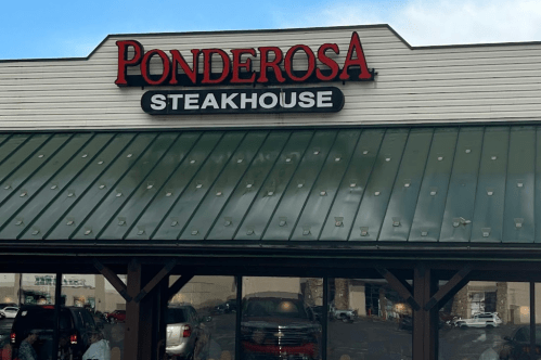 Sign for Ponderosa Steakhouse on a building with a green roof and large windows.