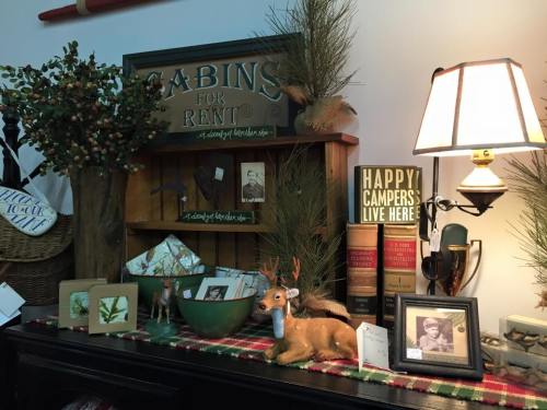 A cozy display featuring rustic decor, including a "Cabins for Rent" sign, framed photos, and a decorative deer.