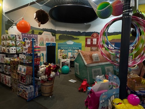 A colorful playroom filled with toys, a bakery mural, and various play structures for children.