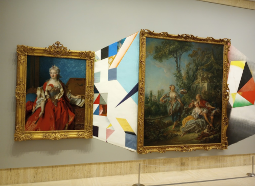 A gallery display featuring two ornate framed paintings, one of a woman in red and another depicting a pastoral scene.