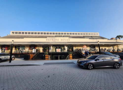 Exterior view of the Packing House, featuring a large building with steps and a parking area in front.