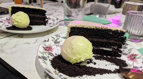 Two plates of chocolate cake with a scoop of vanilla ice cream, served on floral-patterned dishes.