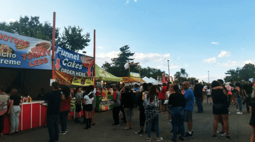 A busy outdoor food festival with various food stalls and a crowd of people enjoying the event.