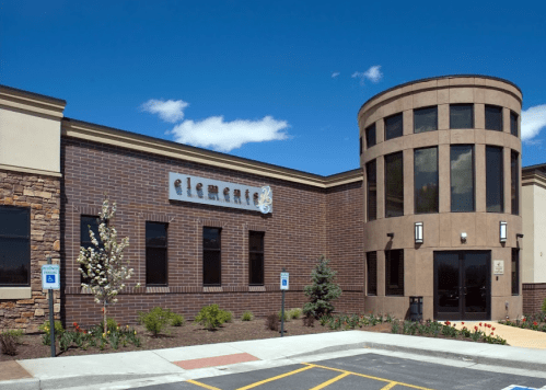 Modern building exterior with a round tower, featuring a sign that reads "elements" and landscaped surroundings.