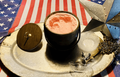 A wooden bowl of pink ice cream on a silver tray, surrounded by patriotic decor and a star-shaped ornament.