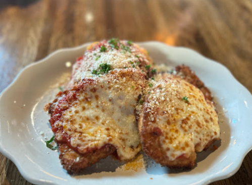 A plate of breaded chicken topped with marinara sauce and melted cheese, garnished with parsley.
