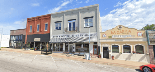 A street view of three storefronts: Bites & Bottle Kitchen Shoppe, a boutique, and La Casita restaurant.