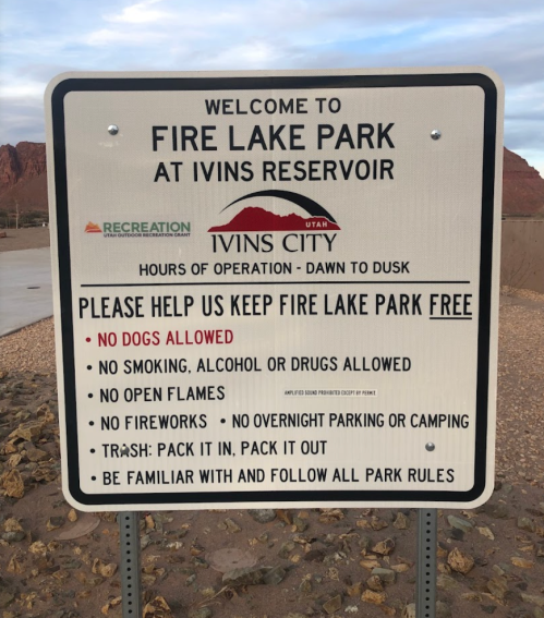 Sign at Fire Lake Park with rules: no dogs, smoking, alcohol, drugs, open flames; pack out trash; follow park rules.