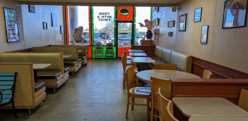 Interior of a casual dining restaurant with booths and tables, featuring colorful decor and large windows.