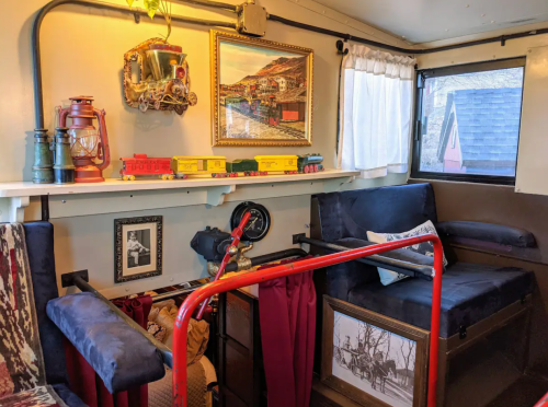 Cozy interior of a vintage train car, featuring decorative items, a window, and seating with a rustic charm.