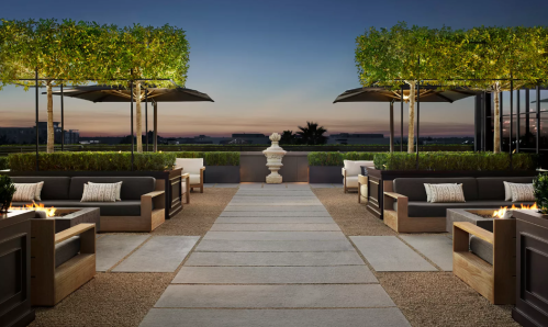 Rooftop patio with modern seating, greenery, and a sunset view, creating a serene outdoor atmosphere.