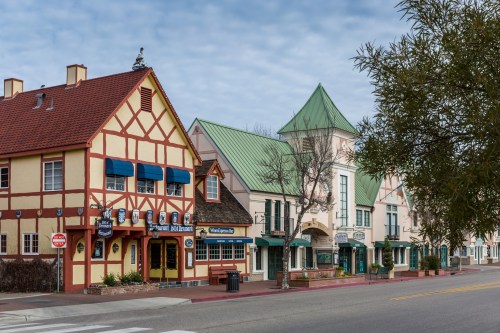Charming street view featuring colorful buildings with unique architectural styles and a cloudy sky.