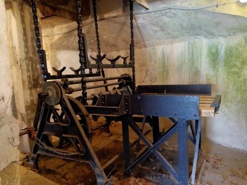 An old, industrial machine with chains and gears, set in a dimly lit, weathered room.