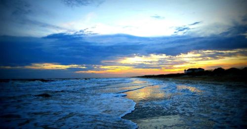 A serene beach at sunset, with gentle waves lapping at the shore and colorful clouds in the sky.