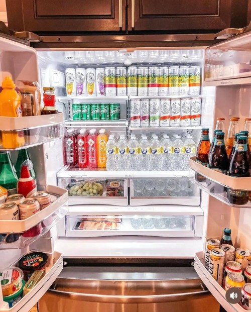 A well-stocked refrigerator filled with various drinks, condiments, and snacks, organized neatly on shelves.